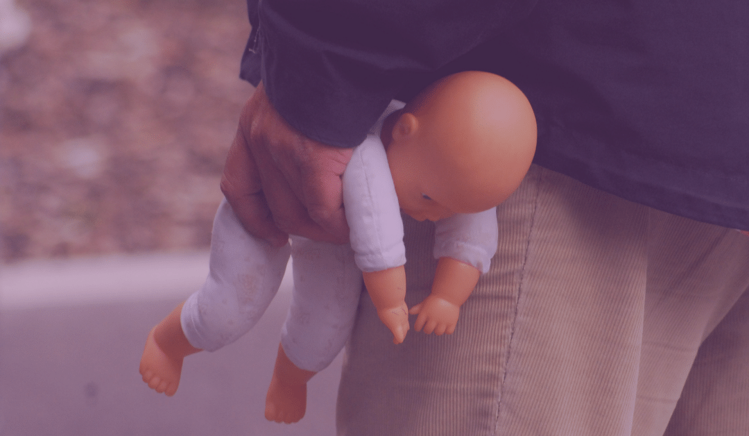 Midsection of adult male holding a baby doll in hand