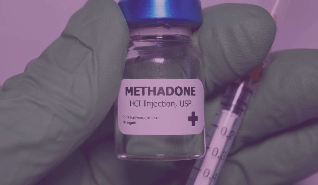 Hand with surgical glove holding a vial of methadone