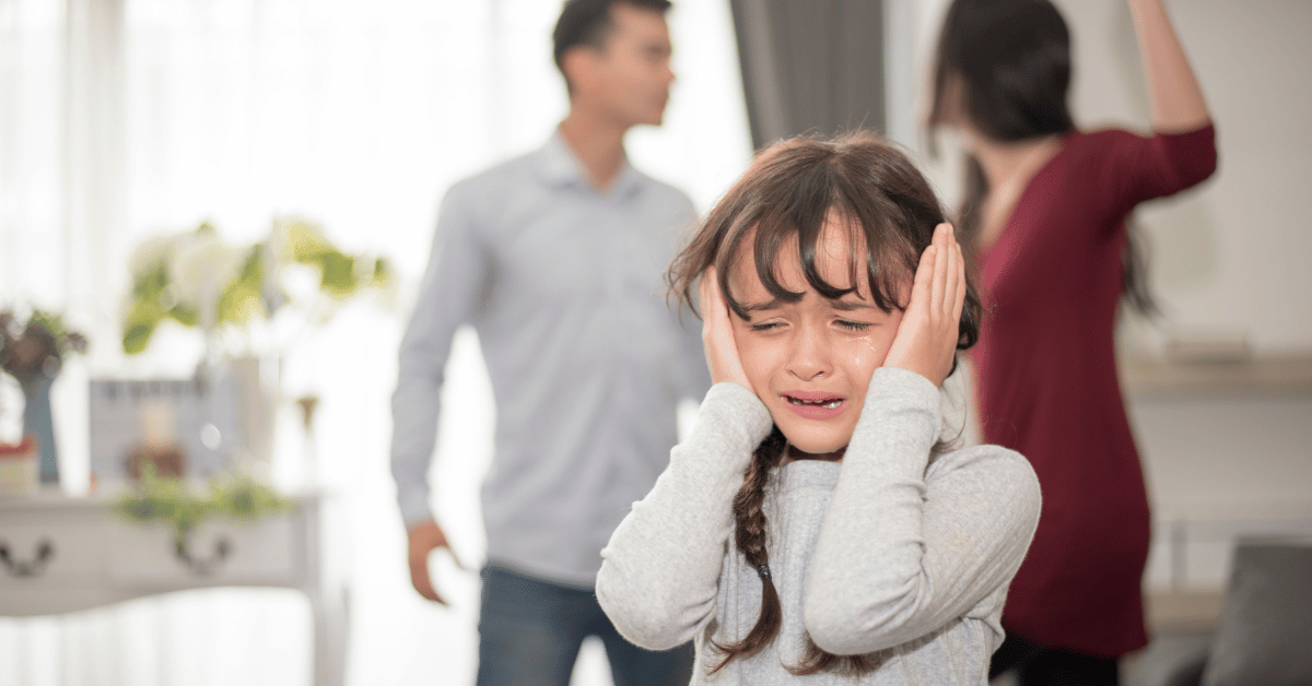 Child covering her ears and crying while her parents argue in the background.