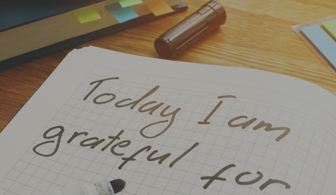 An open grid-lined journal with the words "Today I am grateful for" laying on a desk with a felt-tip marker sitting on the bottom of the page.
