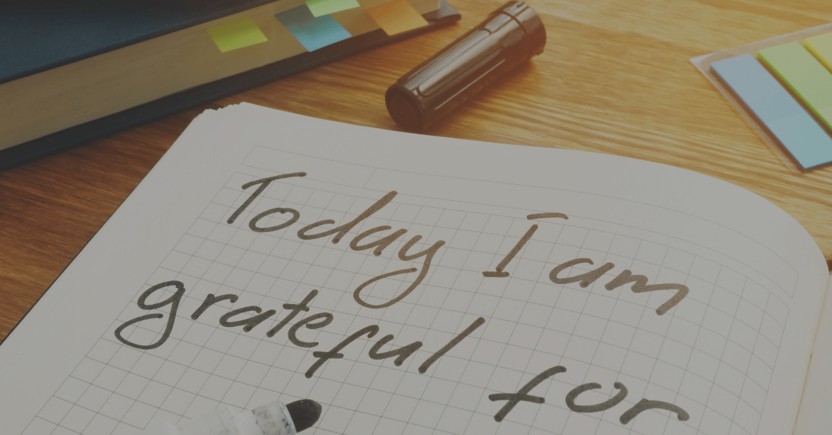 An open grid-lined journal with the words "Today I am grateful for" laying on a desk with a felt-tip marker sitting on the bottom of the page.
